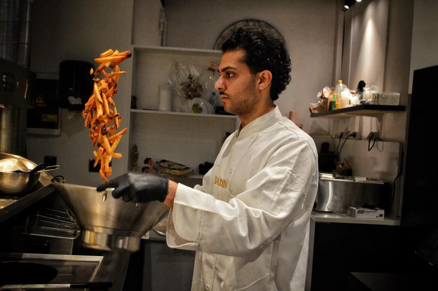 Chef van Batata gooit verse frietjes in de lucht in de keuken